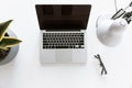 Top view of composition with laptop on white tabletop with glasses, desklamp