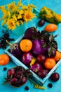 Top view of a composition of purple and yellow vegetables and fruits in a wooden box on a rustic background. Tomatoes, eggplant, Royalty Free Stock Photo