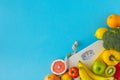 Top view composition of scales and tape measure, plate with fruits and vegetables on blue background Royalty Free Stock Photo