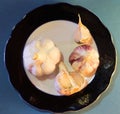 Top view of a composition of young garlic heads on a black and white plate, background