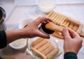 Top view confectioner hands dipping ladyfinger biscuit cookies into a glass of strong sweet espresso coffee. Step-by-step recipe