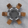 Top view of a conference room. A black round table, six brown leather chairs and six laptops. Office interior.