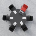 Top view of a conference room. A black round table, six chairs, one of them is red. A laptop and five papers. Royalty Free Stock Photo