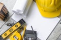 Top view construction tools such as a yellow hard hat, spirit level, measuring tape