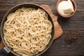 Top view cooked cacio pepe pasta in a skillet with pecorino cheese on wooden background Royalty Free Stock Photo