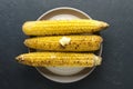 Top view of cooked delicious corn with butter on the plate, dark table