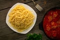 Top view cooked spaghetti in a white plate and a pan with meatballs in tomato sauce