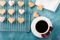 Top view of cookies hearts with icing on metal grate with Cup of red tea and rose on blue background Royalty Free Stock Photo