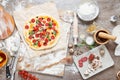 Top view cooking pizza with ingredients, tomatoes, salami and mushrooms on wooden tabletop Royalty Free Stock Photo