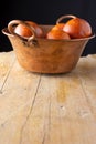 Top view of copper bowl with blood oranges on rustic wooden table, with black background, vertical Royalty Free Stock Photo