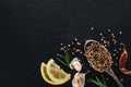 Top view of coriander seeds in silver spoon on black background with dried chili pepper, lemon, herbs and garlic. Royalty Free Stock Photo