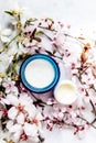 Top view of cosmetic cream and concealer eyes creams with pink cherry flowers in a blue glass jar. Hygienic skincare lotion Royalty Free Stock Photo