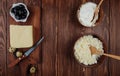 top view of cottage cheese in wooden bowls and a piece of cheese on a wooden cutting board with a kitchen knife , quail eggs and Royalty Free Stock Photo