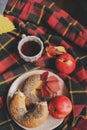 Top view of cozy autumn morning at home. Breakfast with laptop, cup of tea and bagel with apples on woolen plaid blanket Royalty Free Stock Photo