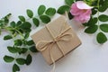 Top view of craft gift box with pink rosehip flowers on white table with copy space. Royalty Free Stock Photo