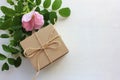 Top view of craft gift box with pink rosehip flowers on white table with copy space. Royalty Free Stock Photo