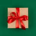 Top view of craft Merry Christmas gift with red bow ribbon over green background Royalty Free Stock Photo