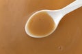 Top view of creamy brown turkey gravy with a white spoon in the food