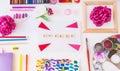 Top view creative artist workplace. Blank canvas with Create word lettering, variety of painting supplies and peony flowers. Royalty Free Stock Photo