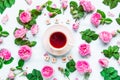 Top view creative layout with Tea time lettering with wooden blocks, cup of hot tea and fresh pink tea rose flowers, buds, petals,