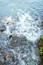 Top view of the creek. Water flows on stones. Bubbles and foam on the water. Abstract natural background