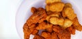 Top view of crispy fried spicy chicken and nuggets on violet or purple plastic dish or plate isolated on white background. Royalty Free Stock Photo