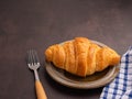 Top view of croissant milk on a plate, cutlery, and a cloth placed on the old kitchen table. Royalty Free Stock Photo