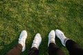 Top view of crop anonymous couple of tourists in sneakers standing on ground with green grass