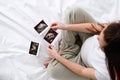 Top view cropped of pregnant woman looking ultrasound photo of fetus standing at home, young future mom waiting child Royalty Free Stock Photo