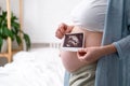 Top view cropped of pregnant woman with ultrasound photo of fetus standing at home, young future mom waiting child first Royalty Free Stock Photo