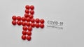 Top view of cross made of red pills and inscription Covid 19 Supportive Care lying diagonally on light background