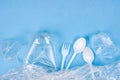 Top view of crushed plastic spoons, forks, bottles and cups as a disposable waste with copy space on bright blue background Royalty Free Stock Photo