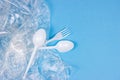 Top view of crushed plastic spoons, forks, bottles and cups as a disposable waste with copy space on bright blue background Royalty Free Stock Photo