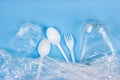 Top view of crushed plastic spoons, forks and cups as a disposable waste with copy space on bright blue background Royalty Free Stock Photo