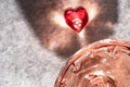 Top view of crystal glass of rose sparkling wine or champagne and red glass heart on grey stone background in hard light