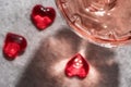 Top view of crystal glass of rose sparkling wine or champagne and red glass hearts on grey stone background in hard