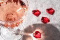 Top view of crystal glass of rose sparkling wine or champagne and red glass hearts on grey stone background in hard