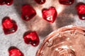 Top view of crystal glass of rose sparkling wine or champagne and red glass hearts on grey stone background in hard