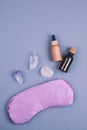 Top view of crystals gemstones minerals, violet purple eye pillow, glass and wooden bottles for essential oils over grey