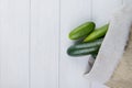 top view of cucumbers spilling out of sack on right side and wooden background with copy space