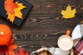 Top view of a cup of coffee, book, plaid scarf, pumpkin and colourful leaves on the wooden table. Slow life concept.