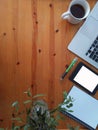 Top view of cup of coffee, keyboard, notebook, tablet, smartphone, green plant and notebook and pen at workplace.