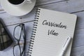 Top view of a cup of coffee,mobile phone,glasses,pen and book written with Curriculum Vitae on wooden background