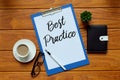 Top view of a cup of coffee,pen,sunglasses,notebook,plant and paper written with Best Practice on wooden background.