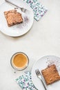 Top view of a cup of coffee and two dessert plates with brownie cake over white rustic background