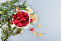 top view of cup full of red cherries on left side and white background decorated with leaves with copy space Royalty Free Stock Photo
