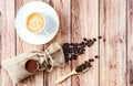 Top view of a cup of hot coffee and coffee beans in a wooden scoop and spilling out from a hessian bag on wooden rustic Royalty Free Stock Photo