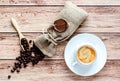 Top view of a cup of hot coffee and coffee beans in a wooden scoop and spilling out from a hessian bag on wooden rustic Royalty Free Stock Photo