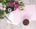 Top view of cup of tea, flowers, vintage camera, earphones, pen Royalty Free Stock Photo