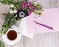 Top view of cup of tea, flowers, vintage camera, earphones, pencils and sheet of paper Royalty Free Stock Photo